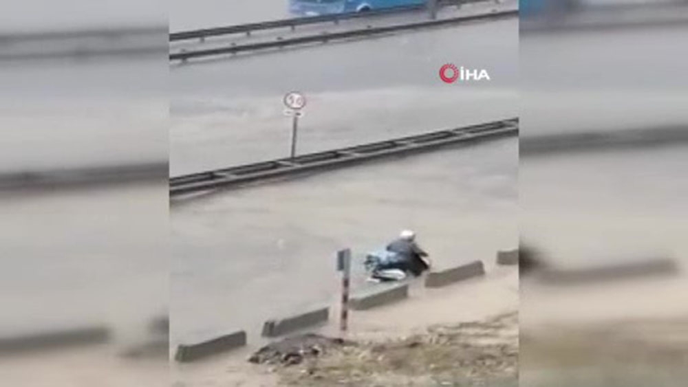 Aşırı yağışa aldırmadı, motosikletini sele kaptırdı